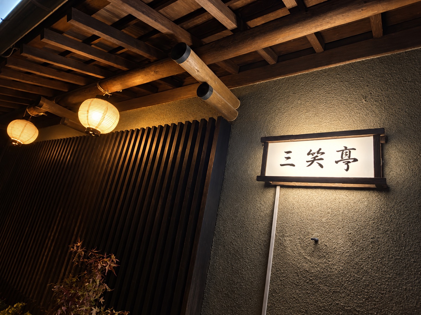 灯りがともる三笑亭の入口と看板